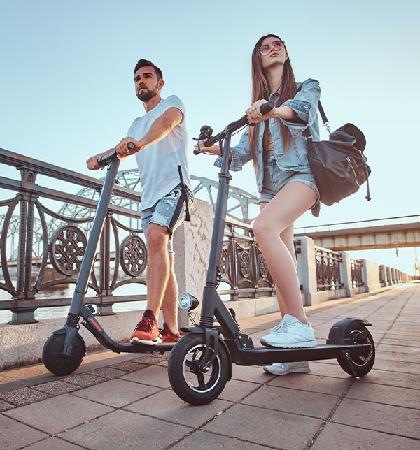 couple en trottinette électrique circulant en ville - Avec la SMENO, déplacez vous en NVEI en toute sécurité avec l'assurance NVEI