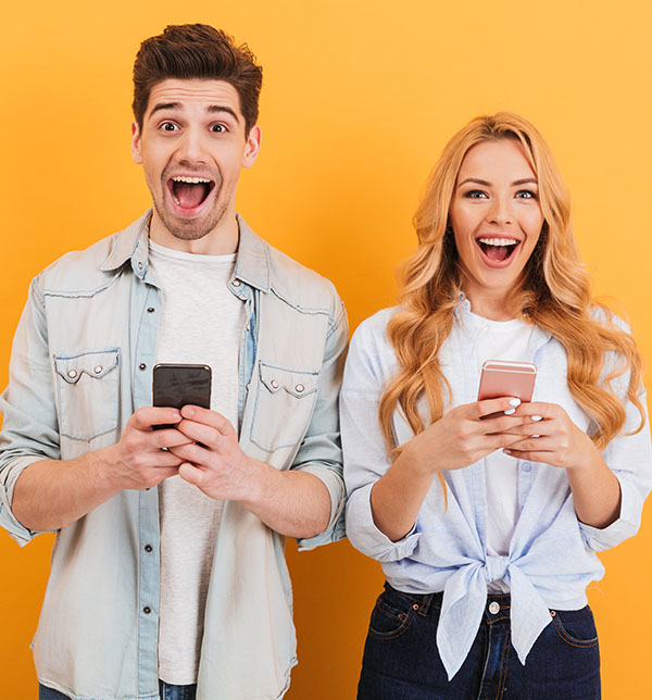 Deux étudiants souriant se servant de leur téléphone - La SMENO assure votre colocation en cas de bail collectif