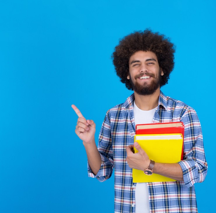 Jeune étudiant portant ses livres qui pointe vers la gauche - La mutuelle d'entreprise vous coûte la moitié de son prix grâce à votre employeur !