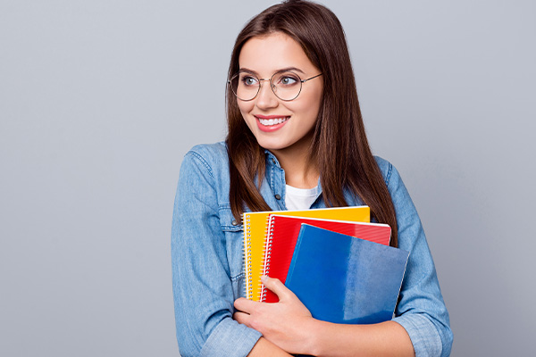 lycéenne souriante portant ses manuels scolaires - La SMENO aide les lycéens à trouver un job 